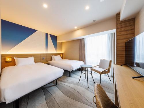 a hotel room with two beds and a television at JR East Hotel Mets Premier Makuhari Toyosuna in Chiba