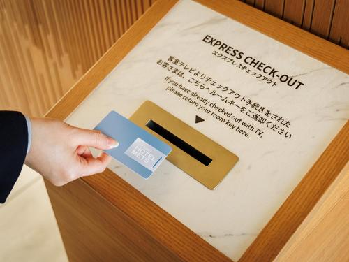 a hand holding a card and a pen on a piece of paper at JR East Hotel Mets Premier Makuhari Toyosuna in Chiba