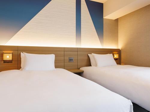 two beds sitting next to each other in a room at JR East Hotel Mets Premier Makuhari Toyosuna in Chiba