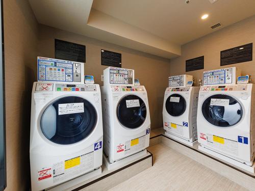 four washing machines are lined up in a laundry room at JR East Hotel Mets Premier Makuhari Toyosuna in Chiba
