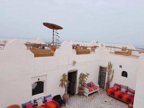 a white building with red and blue couches at Riad Sahara Sunset Beach Douira Agadir in Douaïra
