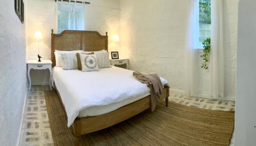 Un dormitorio con una cama grande con sábanas y almohadas blancas. en Cosy, romantic, private cottage, close to all & pet friendly, en Healesville