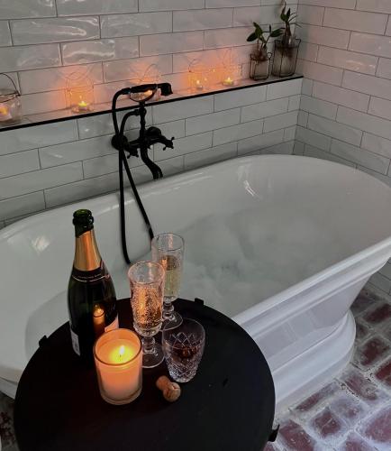 a bath tub with a bottle of champagne and candles at ONE WEE COTTAGE Bring your dog and enjoy a cosy romantic winter fireside stay in Healesville