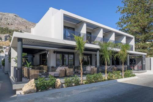 a white house with palm trees in front of it at Evanik Chic Hotel in Kalymnos