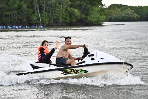 a man and woman riding on a jet ski in the water at Cần Giờ Floating House in Ấp Phước Thới