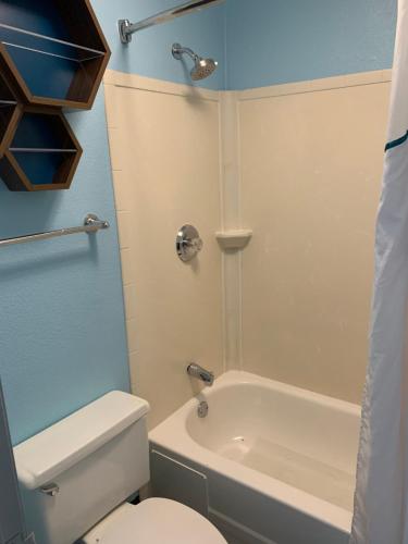 a bathroom with a white toilet and a bath tub at HomeTowne Studios by Red Roof Mystic - New London in New London