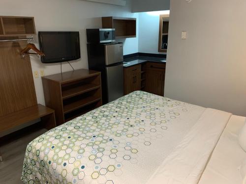 a small kitchen with a bed and a television at HomeTowne Studios by Red Roof Mystic - New London in New London