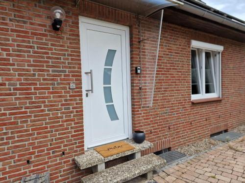 a white door on a brick building with a stairs at Heide-Marie, Ferienhaus in Schneverdingen