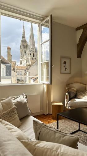 un salon avec un canapé et une grande fenêtre dans l'établissement Cœur Cathédrale - Charme et vue fantastique, à Chartres