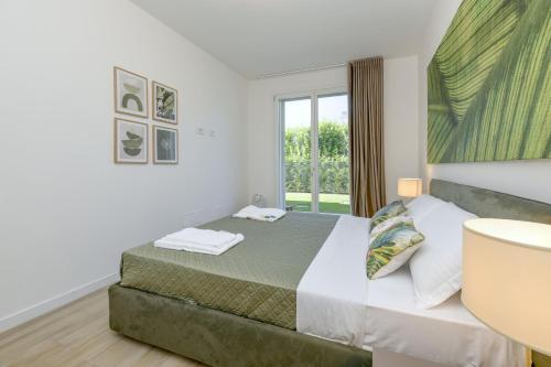 a white bedroom with a bed and a window at MGH Luxury - Vivere il Lago C05 in Desenzano del Garda