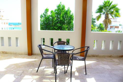 a table and chairs on a patio with two windows at Wateera Jebel Sifah in As Sīfah