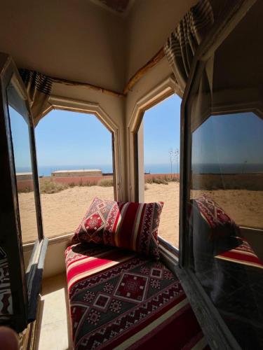 a bed in a train with two windows and a beach at Riad Sahara Sunset Beach Douira in Agadir