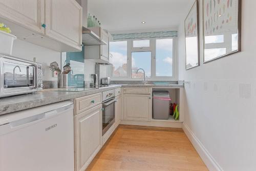 a kitchen with white cabinets and a counter top at The Crows Nest - Apartment with great sea views- Crabpot Cottages Sheringham in Sheringham