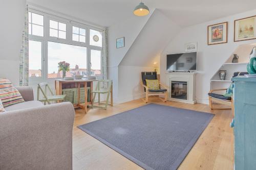 a living room with a couch and a fireplace at The Crows Nest - Apartment with great sea views- Crabpot Cottages Sheringham in Sheringham