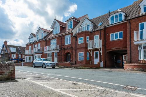 a car parked in front of a row of brick houses at The Crows Nest - Apartment with great sea views- Crabpot Cottages Sheringham in Sheringham