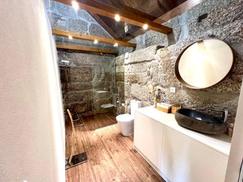 bagno con parete in pietra e specchio di Wine Press INN ad Amarante