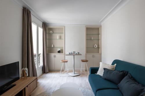 un salon avec un canapé bleu et une télévision dans l'établissement Appartement Hermosa - Welkeys, à Paris