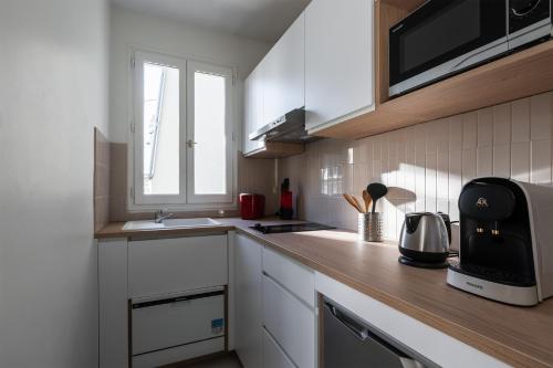une cuisine avec des armoires blanches et un comptoir dans l'établissement Appartement Hermosa - Welkeys, à Paris