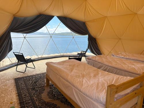 a bedroom with two beds and a view of the ocean at Son-Köl Glamping in Song-Kul