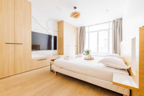 une chambre avec un grand lit blanc et une télévision dans l'établissement Magnificent apartment - 3BR-6P - Europe, à Paris