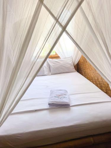 a bed in a tent with a shirt on it at 360 Surf Camp in Kuta Lombok
