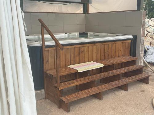 a jacuzzi tub with a wooden fence and a wooden bench sidx sidx at אגם ריזורט בטבע in Kallanit