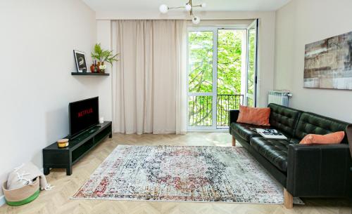 sala de estar con sofá de cuero negro y TV en Koszykowa 3 - Better Rental, en Varsovia