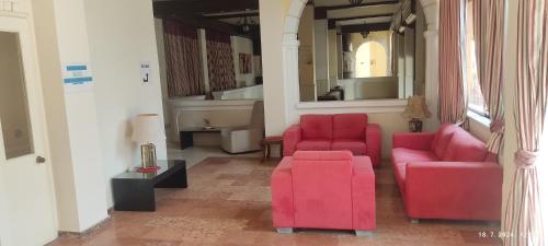 a living room with two red chairs and a table at PANTHEON HALL HOTEL in Mesongi