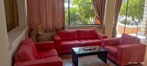a living room with red couches and a table at PANTHEON HALL HOTEL in Mesongi
