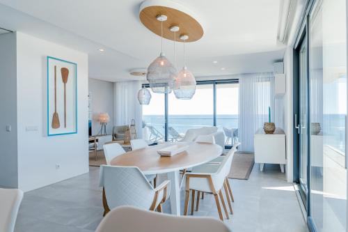 a dining room with a table and white chairs at Shantivillas Portimão in Portimão