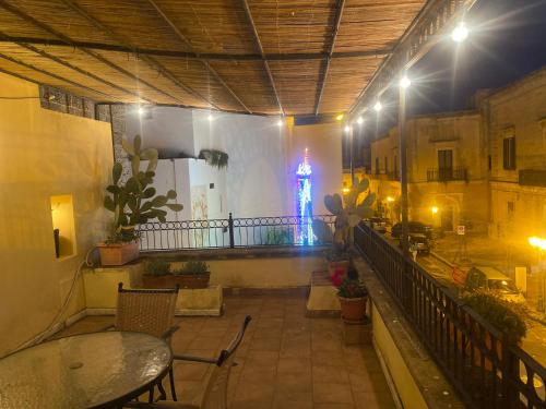 ein Balkon mit Tischen und einem Uhrturm im Hintergrund in der Unterkunft B&B Portaterra in Racale