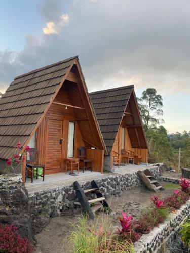 two wooden cabins with a stone wall at D' Tepi Danau Glamping in Kintamani