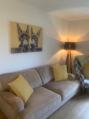 a living room with a couch and a painting of two horses at Ekerveley Lodge in Ballyvoy