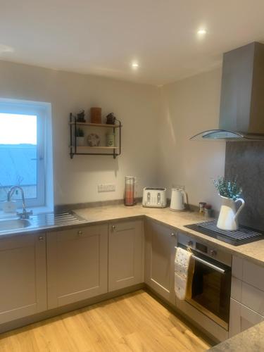 a kitchen with white cabinets and a sink and a window at Ekerveley Lodge in Ballyvoy