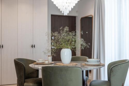 a dining room with a table with chairs and a vase at Pušų terasos 1 in Klaipėda