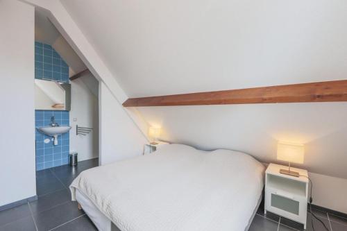 a small bedroom with a white bed and a sink at Weststraat 22 - Ouddorp - Appartement Oost 3P in Ouddorp