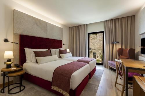 a hotel room with a large bed and a desk at NEYA Porto Hotel in Porto