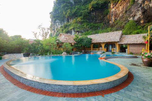 a large blue swimming pool in front of a mountain at Xuan Son Lakeside Bungalow in Ninh Binh