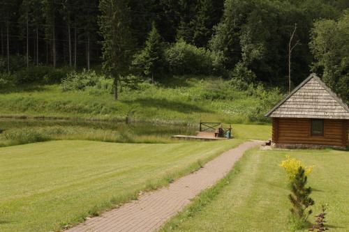 a cabin in the middle of a field with a dirt road at Šnekučių kaimas in Miežonys