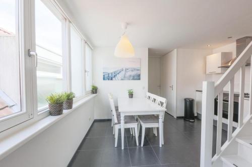 a white dining room with a white table and chairs at Weststraat 22 - Ouddorp - Appartement Oost 3P in Ouddorp
