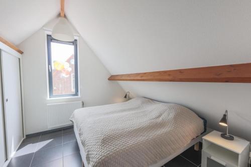 a small attic bedroom with a bed and a window at Weststraat 22 - Ouddorp - Appartement Oost 3P in Ouddorp