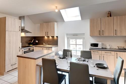 une cuisine avec une table et des chaises dans une cuisine dans l'établissement Les Marmottes - Charmant Appt pour 7 p, à Gérardmer