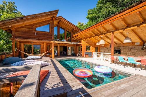 une maison en bois avec piscine et patio dans l'établissement Chalet FLOCON Serre Chevalier cinéma sauna jaccuzi, piscine été, à Briançon