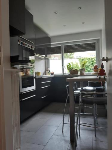 une cuisine avec des armoires noires, une table et des chaises dans l'établissement Charmant appart. ouest parisien, à Boulogne-Billancourt