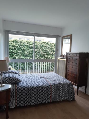 une chambre avec un lit et une grande fenêtre dans l'établissement Charmant appart. ouest parisien, à Boulogne-Billancourt