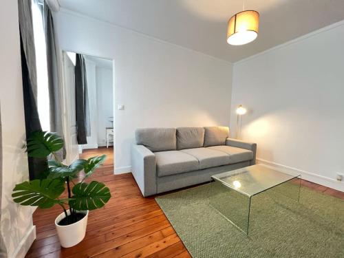 un salon avec un canapé et une table en verre dans l'établissement Appartement Neuf Proche de Paris, à Saint-Denis