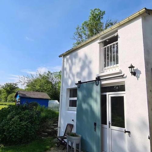 une maison blanche avec une porte verte et une chaise dans l'établissement Le gîte des Allains, à Sainte-Suzanne-en-Bauptois
