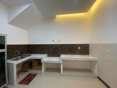 a bathroom with white counters and a sink at Kanggo Riko Family Homestay Mitra Reddoorz in Banyuwangi