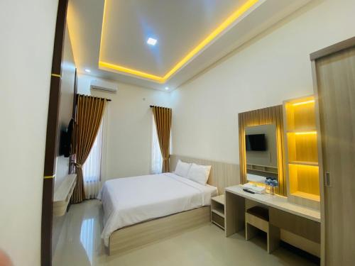 a hotel room with a bed and a television at Kanggo Riko Family Homestay Mitra Reddoorz in Banyuwangi