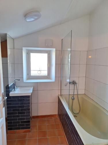 La salle de bains est pourvue d'un lavabo, d'une baignoire et d'une fenêtre. dans l'établissement La Maison Cassée, à Malemort-du-Comtat